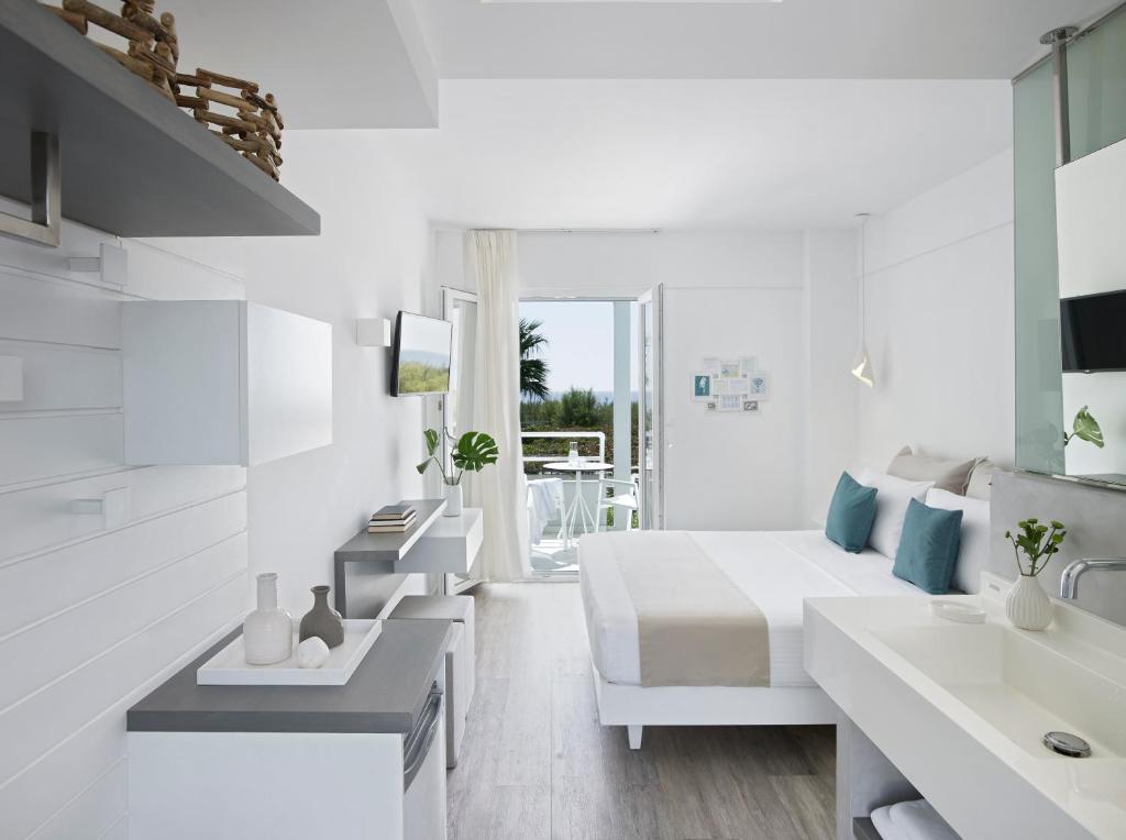 a white bedroom with a bed and a sink at Kouros Seasight Hotel in Pythagoreio