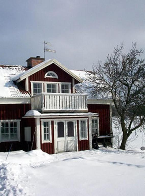 una casa con nieve en el suelo delante de ella en Smultronboda Fårgård, en Edsbruk