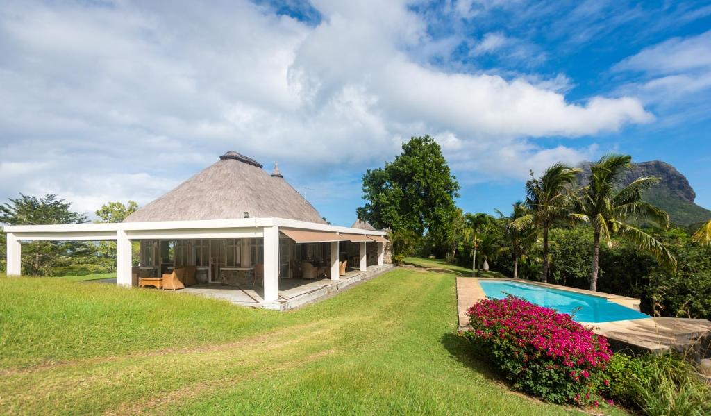 a villa with a thatched roof and a swimming pool at Le Petit Morne Lodge in Le Morne
