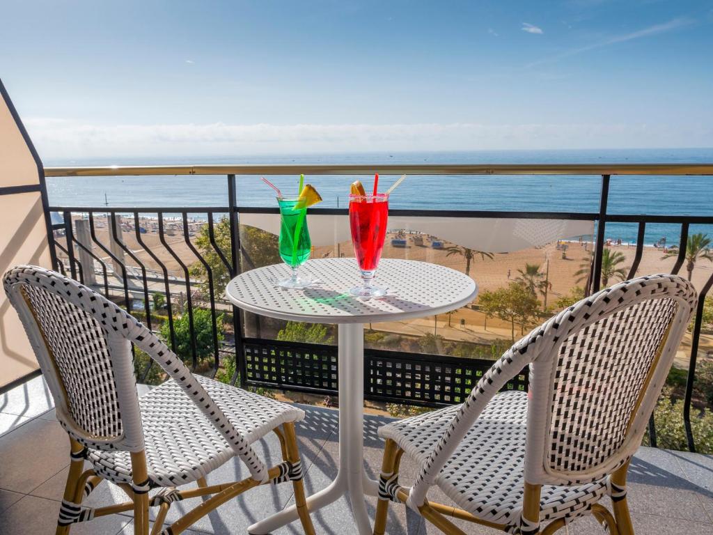 una mesa con 2 bebidas en un balcón con vistas a la playa en Checkin Garbí, en Calella