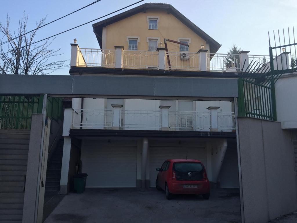 a red car parked in a garage under a house at Apartments Villa Irma in Sarajevo