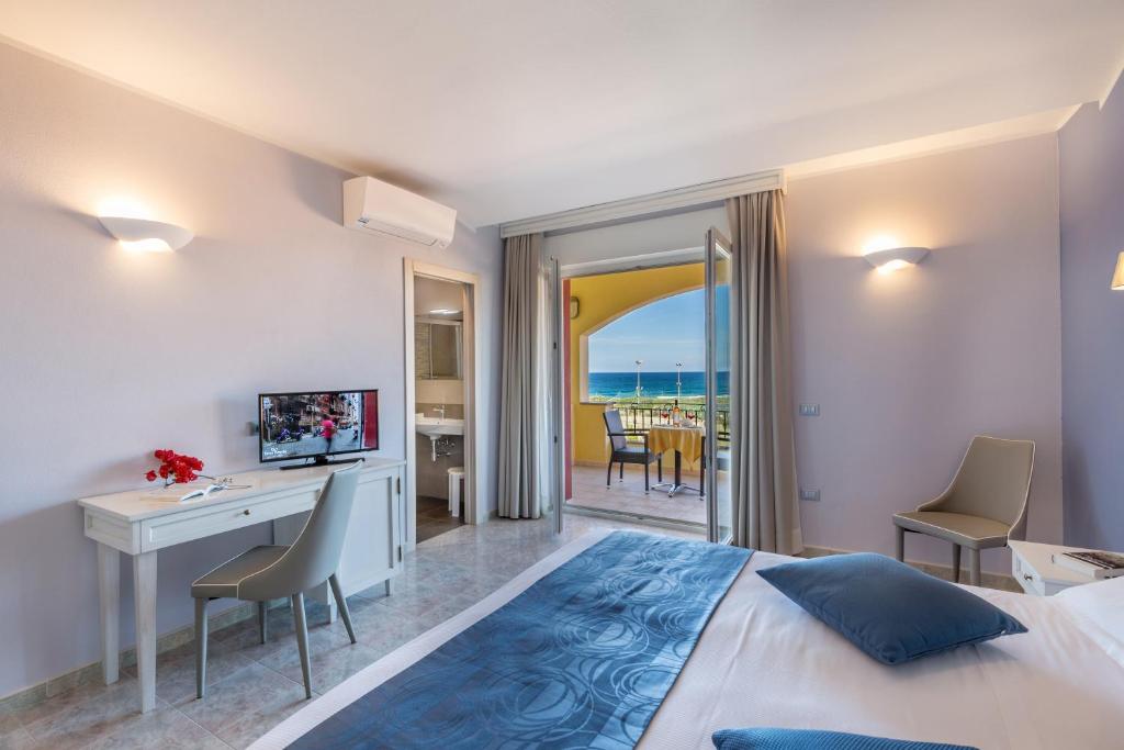 a hotel room with a bed and a desk and a view at Hotel Rosa dei Venti in Castelsardo