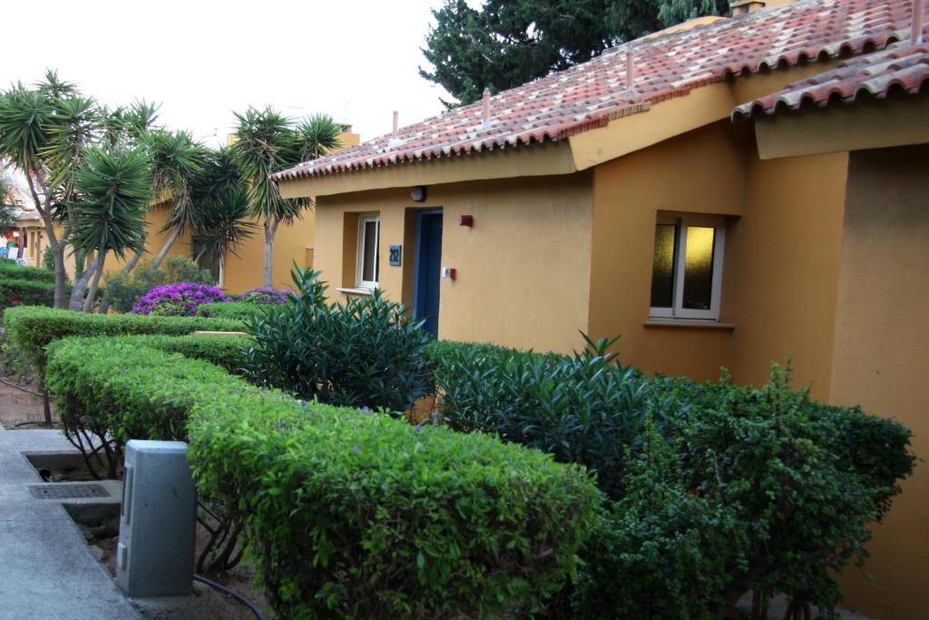 a house with a row of hedges in front of it at Makronisos Village in Ayia Napa