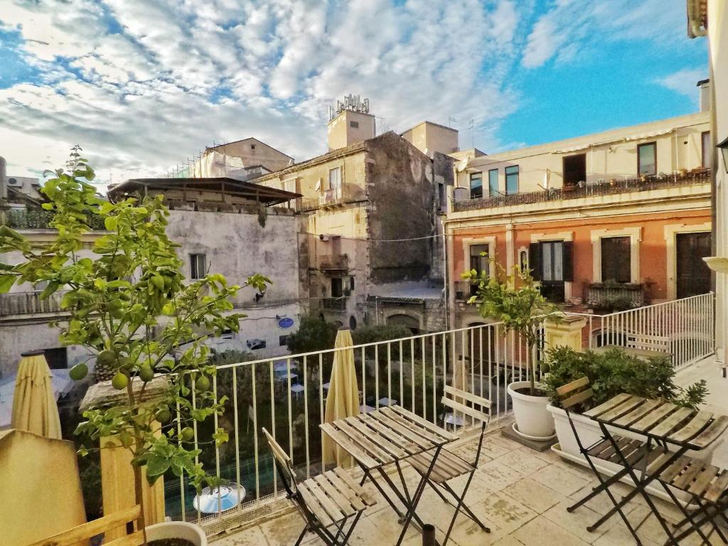 a balcony with chairs and trees and buildings at La Residenza del Reginale in Syracuse