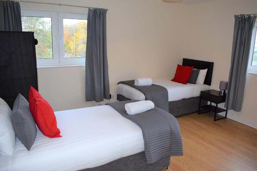 a room with two beds with red and white pillows at Kelpies Serviced Apartments Callum- 3 Bedrooms- Sleeps 6 in Livingston