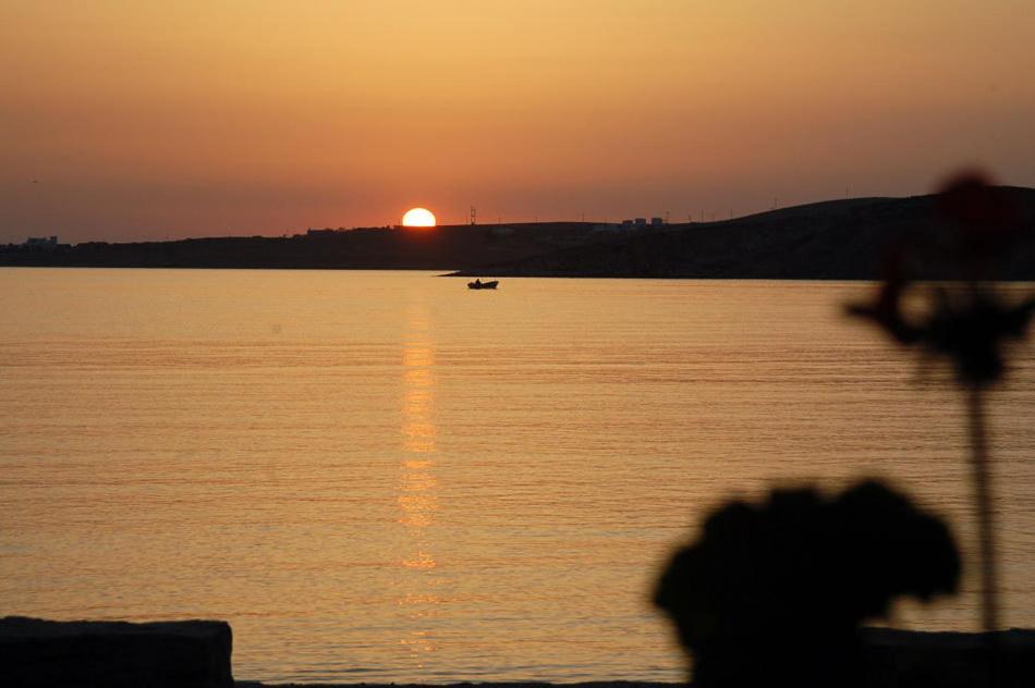 a sunset over a body of water with a boat at Hotel Paros in Parikia