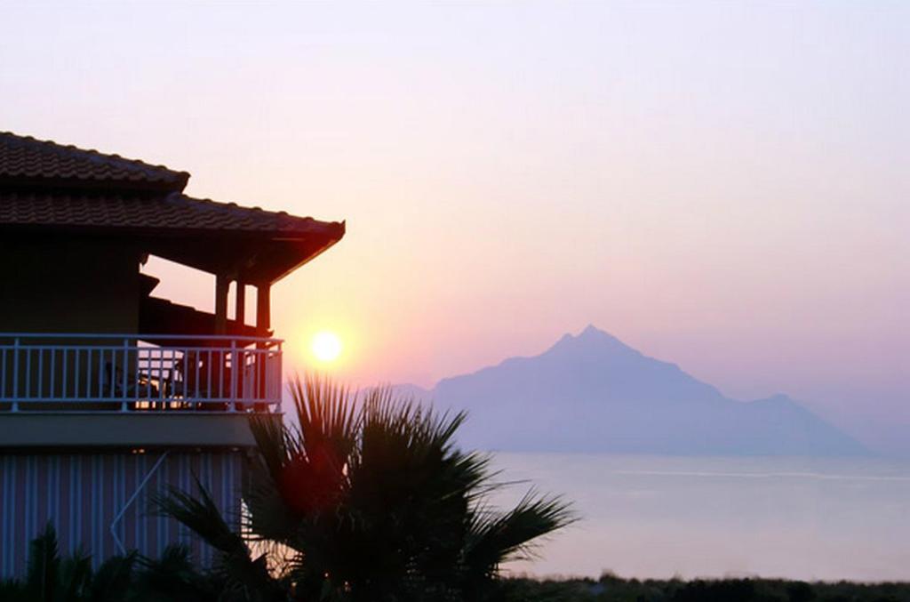 a sunset with a house and a mountain in the background at Erifili at Sarti Beach Apartments & Studios in Sarti