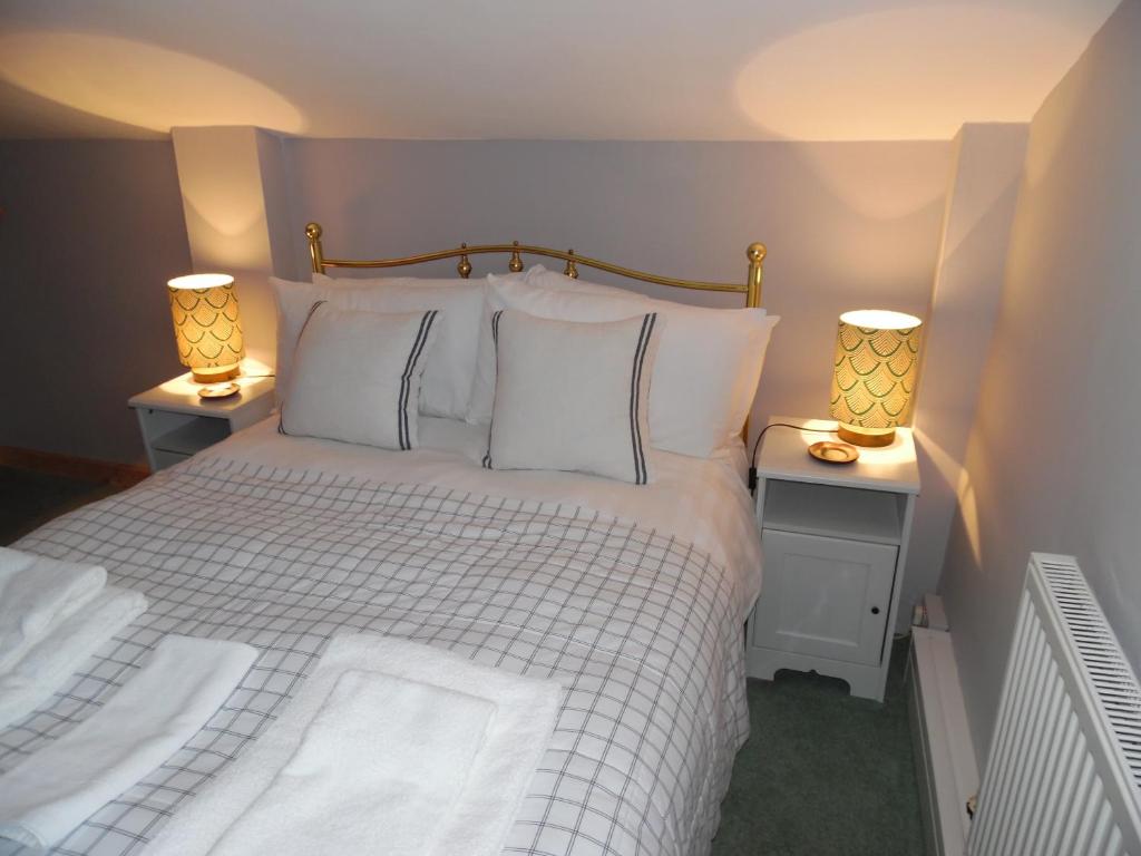 a bedroom with a white bed with two lamps at The Den in Egloskerry