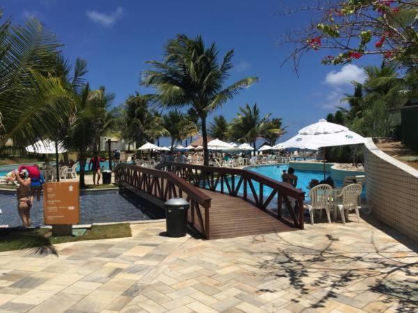 einen Holzsteg, der zu einem Pool in einem Resort führt in der Unterkunft Beach Class Muro Alto - flat in Porto De Galinhas