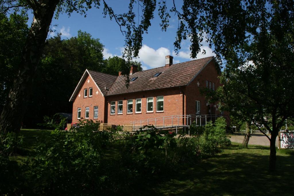 uma grande casa de tijolos vermelhos com telhado em Hallandsåsen Hostel em Hjärnarp
