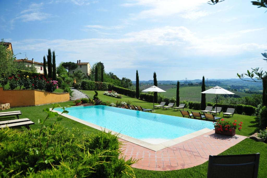 a swimming pool in a yard with chairs and umbrellas at La Corte D'Elsa in Castelfiorentino