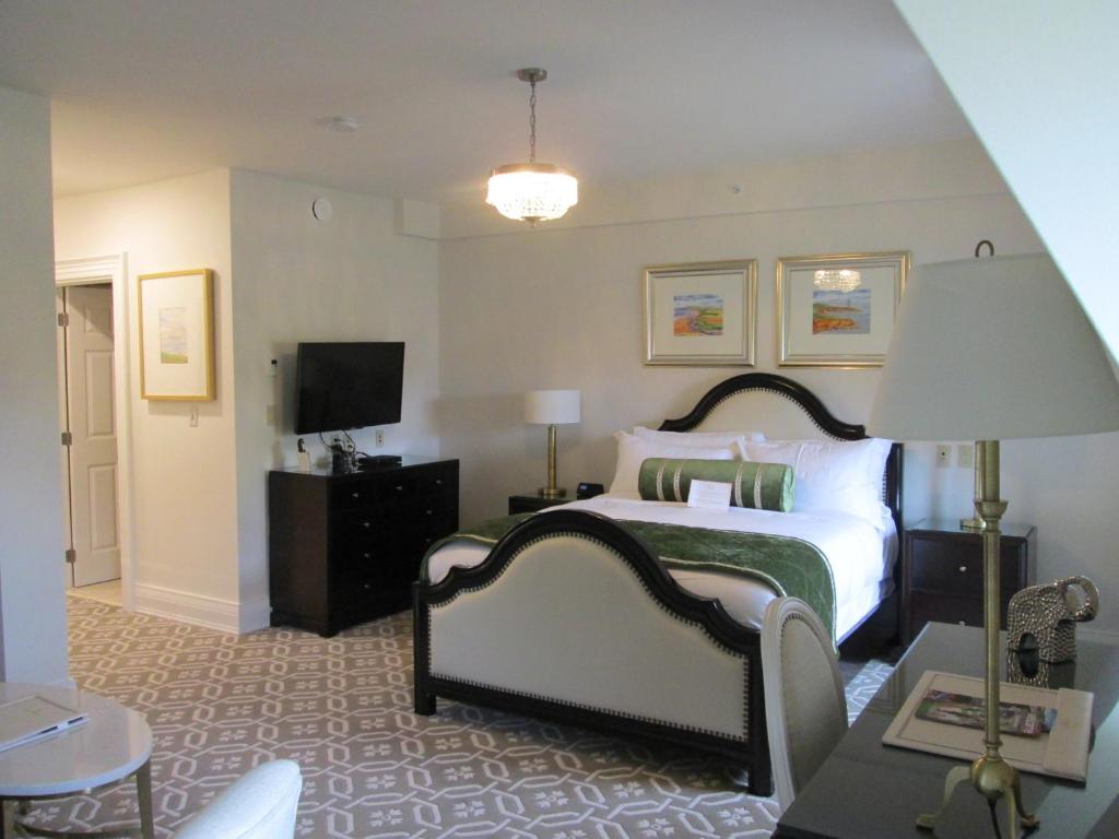 a bedroom with a bed and a lamp and a tv at Sydney Boutique Inn & Suites in Charlottetown