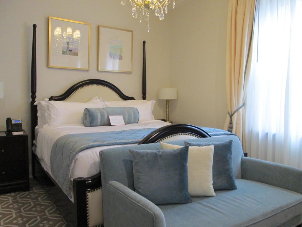 a bedroom with a bed and a couch with pillows at Sydney Boutique Inn & Suites in Charlottetown
