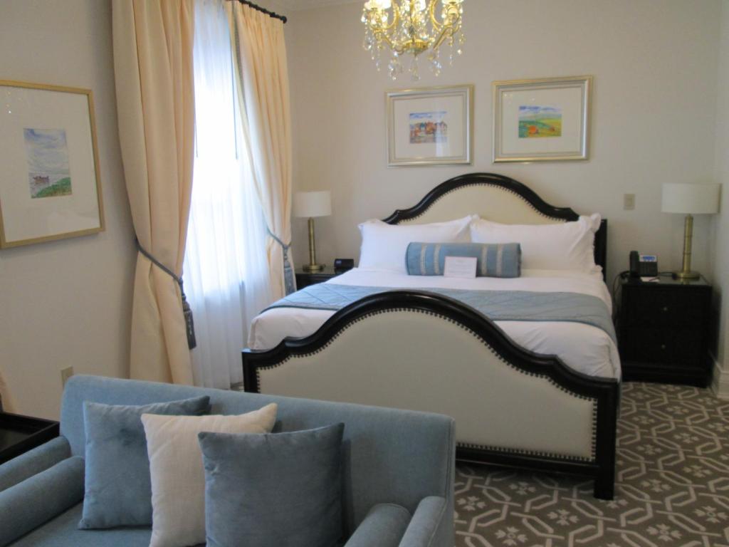 a bedroom with a bed and a couch and a chandelier at Sydney Boutique Inn & Suites in Charlottetown