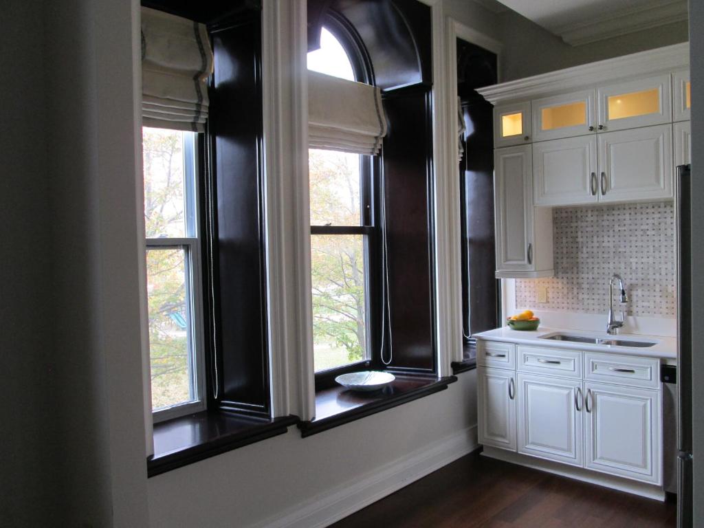 a kitchen with white cabinets and two windows at Sydney Boutique Inn & Suites in Charlottetown