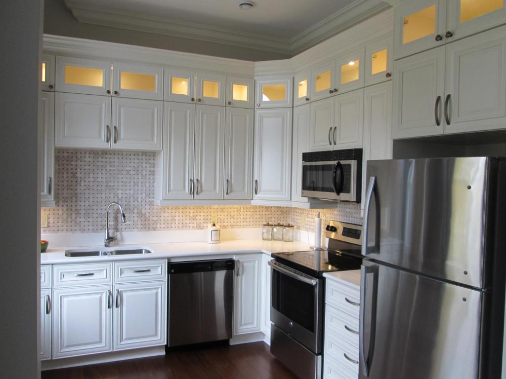 a kitchen with white cabinets and a stainless steel refrigerator at Sydney Boutique Inn & Suites in Charlottetown