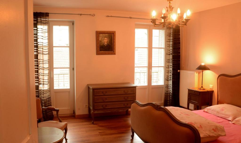 a bedroom with a bed and a table and windows at Residence des Bains in Plombières-les-Bains