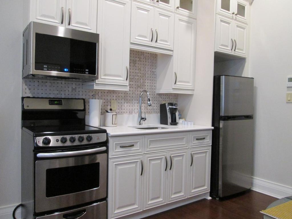 a kitchen with white cabinets and a stainless steel refrigerator at Sydney Boutique Inn & Suites in Charlottetown
