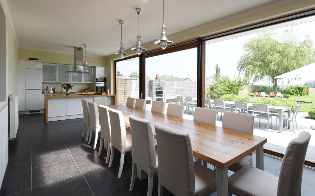 uma cozinha e sala de jantar com uma mesa de madeira e cadeiras em Rue du Canal em Alveringem