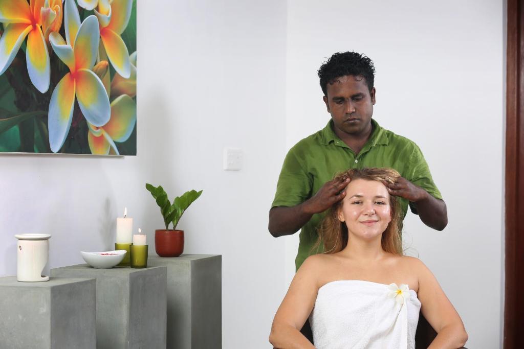 a man cutting a girls hair in a mirror at Villa Velmarie Yoga and Ayurveda house all inclusive in Beruwala