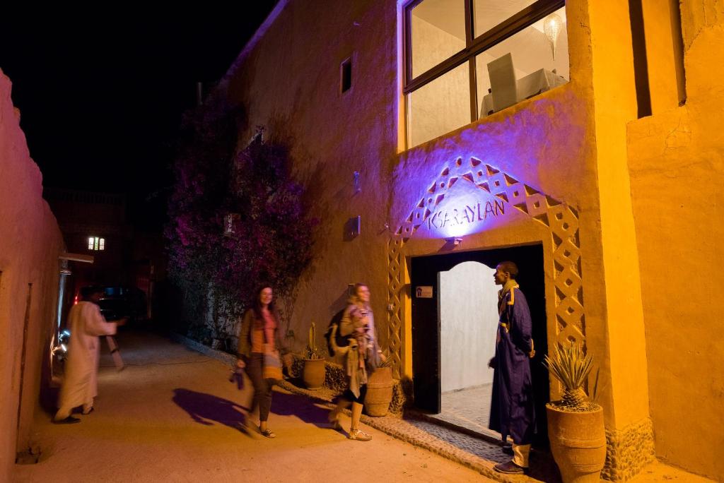 un grupo de personas de pie fuera de un edificio por la noche en Riad Ksar Aylan, en Ouarzazate