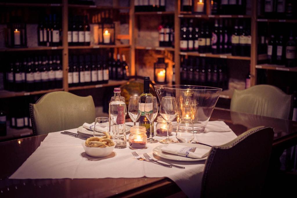 a table in a wine cellar with wine bottles and glasses at Hotel Ristorante La Perla in Varallo Pombia