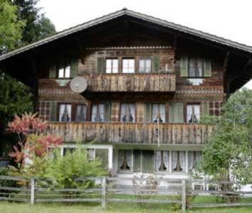 Cette grande maison en bois possède un balcon. dans l'établissement Chalet Kanderhus, à Kandersteg