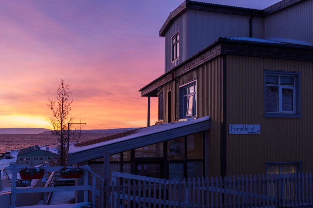 een gebouw met een zonsondergang op de achtergrond bij Finna Hótel in Hólmavík