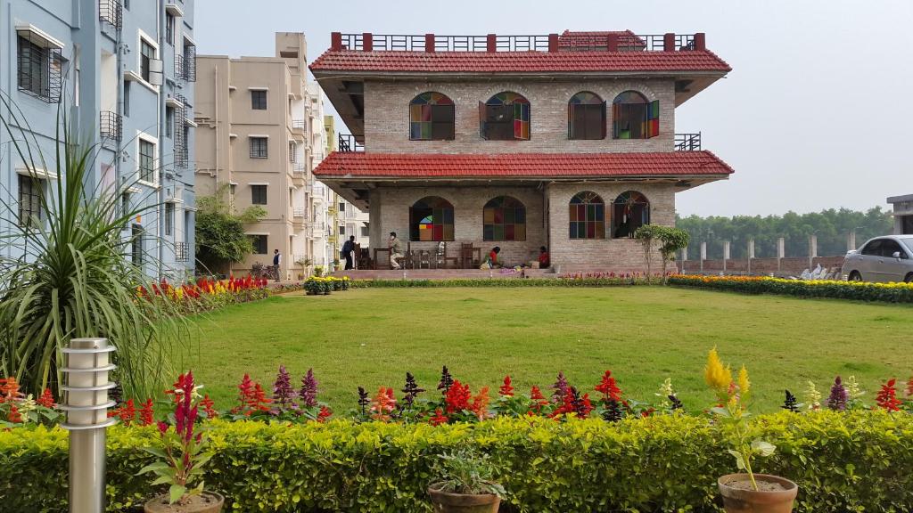 un edificio con un patio con flores delante en Panthashala Santiniketan en Srī Niketan