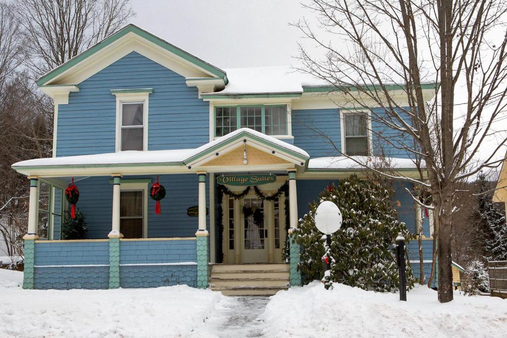 Uma casa azul com grinaldas de Natal à frente. em Village Suites em Margaretville
