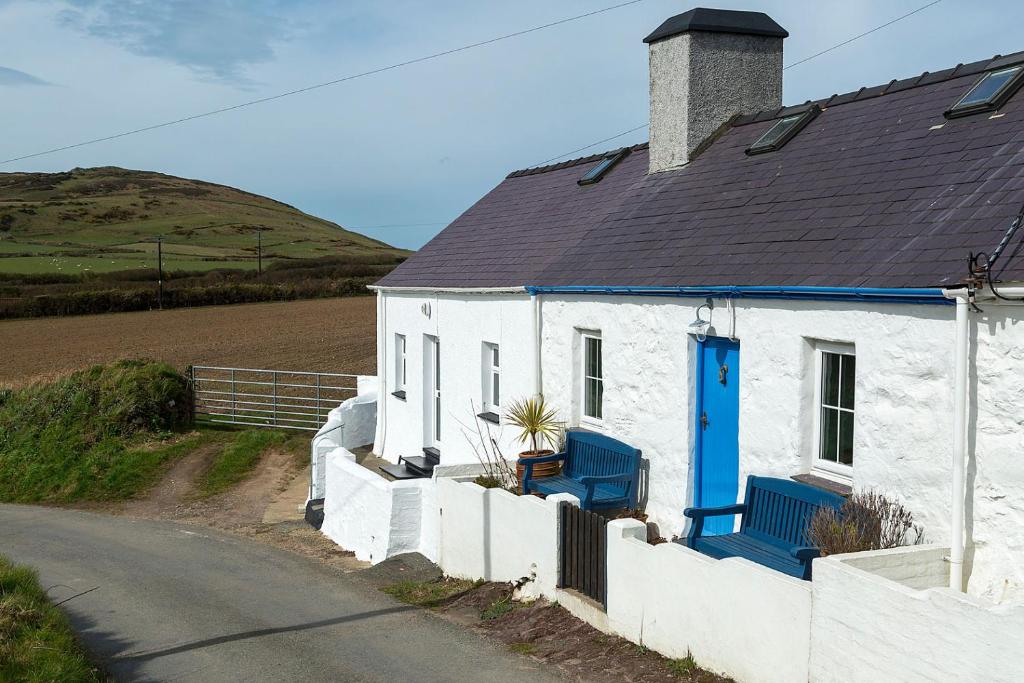a white house with a blue door and a road at Aberdaron Cottage 2 Bryn Chwilog in Aberdaron
