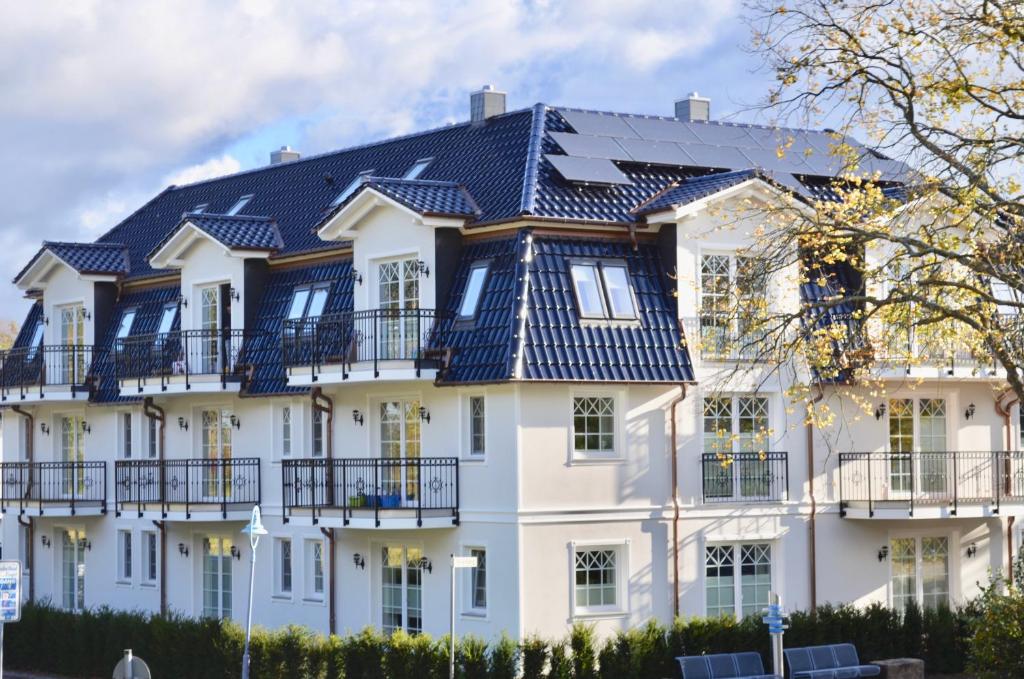 une grande maison blanche avec un toit noir dans l'établissement Villa Strandblick 7, à Zingst