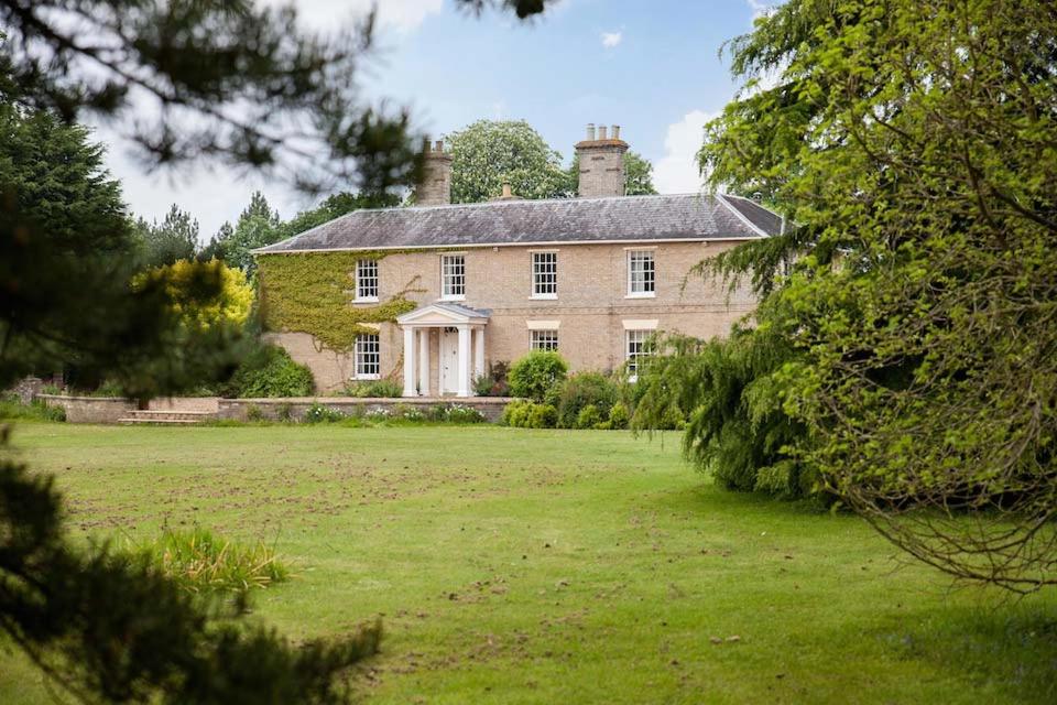 ein altes Steinhaus mit großem Rasenplatz in der Unterkunft Vicarage House & Pool House in Hockham