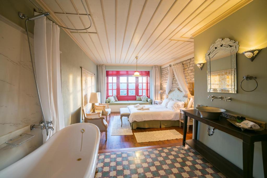 ein Badezimmer mit einer Badewanne und ein Schlafzimmer mit einem Bett in der Unterkunft Primoula Country Hotel & Spa in Ano Pedina