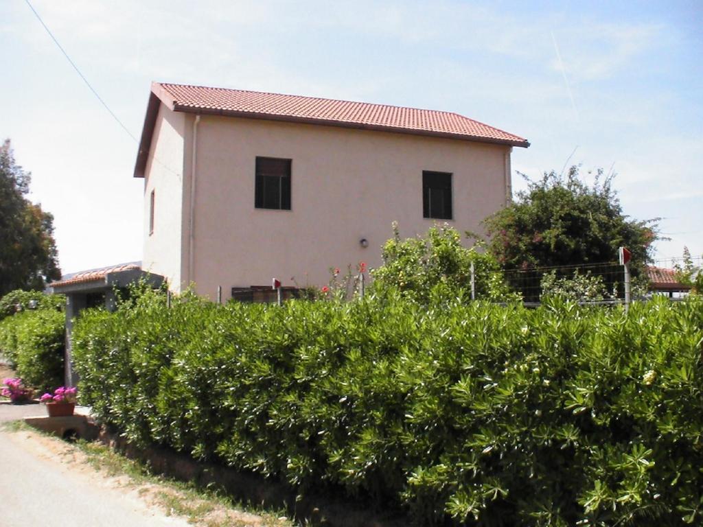 une maison avec une rangée de buissons devant elle dans l'établissement Villa Pietrina del Mejlogu, à Fertilia