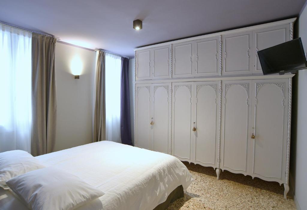 a bedroom with a large white bed and a tv at Arsenale 3880 in Venice