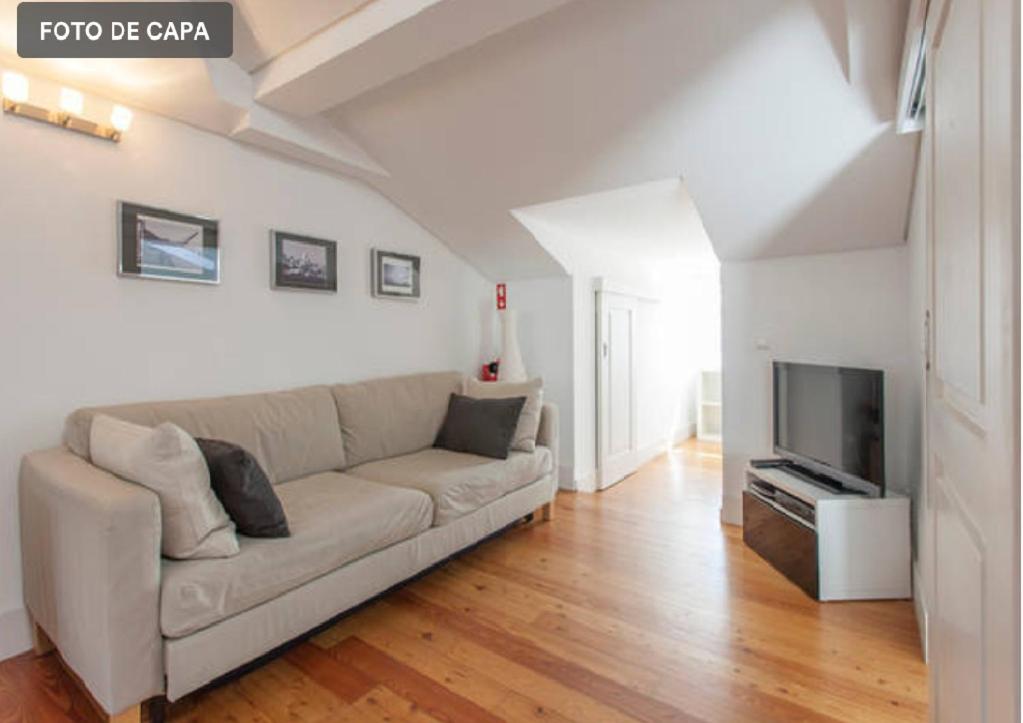 sala de estar con sofá y TV en Casas São Julião, en Lisboa