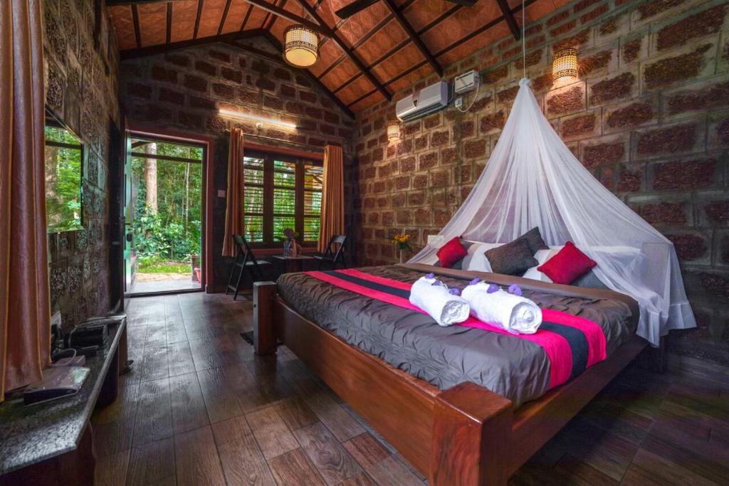 a bedroom with a bed with a mosquito net at The Copper Edge in Kodlipet