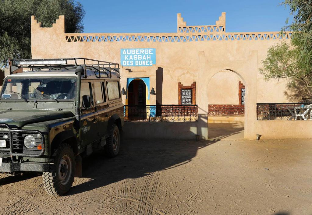 einem grünen LKW, der vor einem Gebäude parkt in der Unterkunft Auberge Kasbah Des Dunes in Merzouga