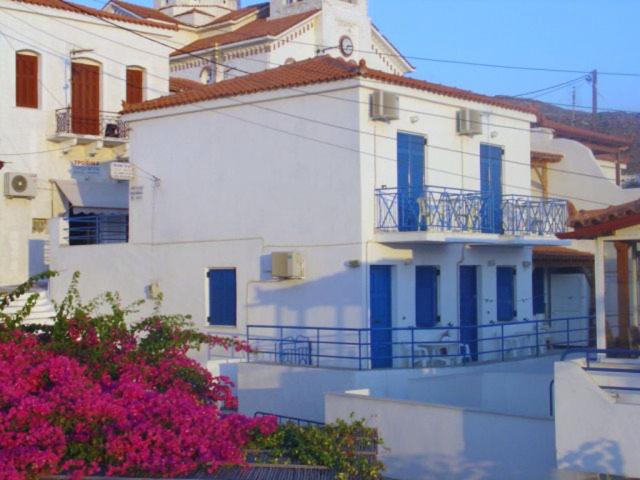 a large white building with blue windows and flowers at Villa Aegeo Studios in Batsi