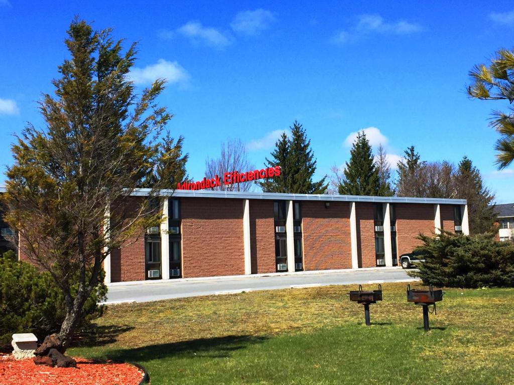 a large brick building with a red sign on it at Adirondack Efficiencies in Watertown