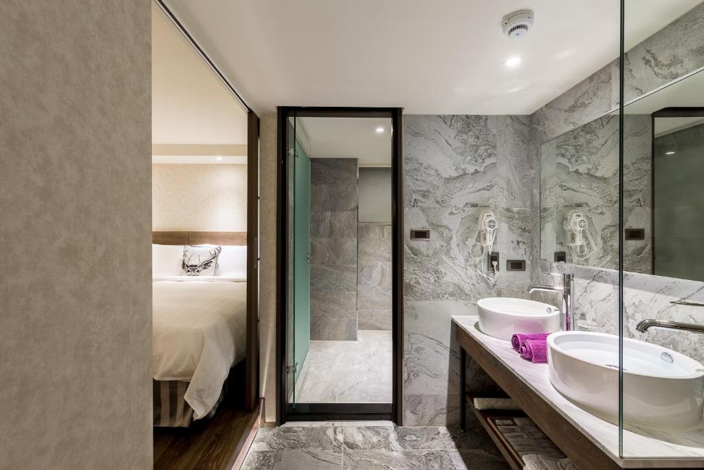 a bathroom with two sinks and a shower and a bed at Lan Kwai Fong Garden Hotel in Chiayi City