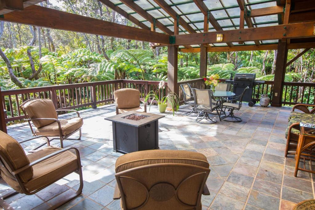 a patio with chairs and a table and a stove at Hale Mauna Loa Upper Level with shared Hot Tub in Volcano