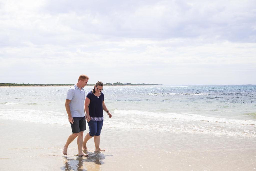 a man and a woman walking on the beach at Ingenia Holidays Torquay Australia in Torquay