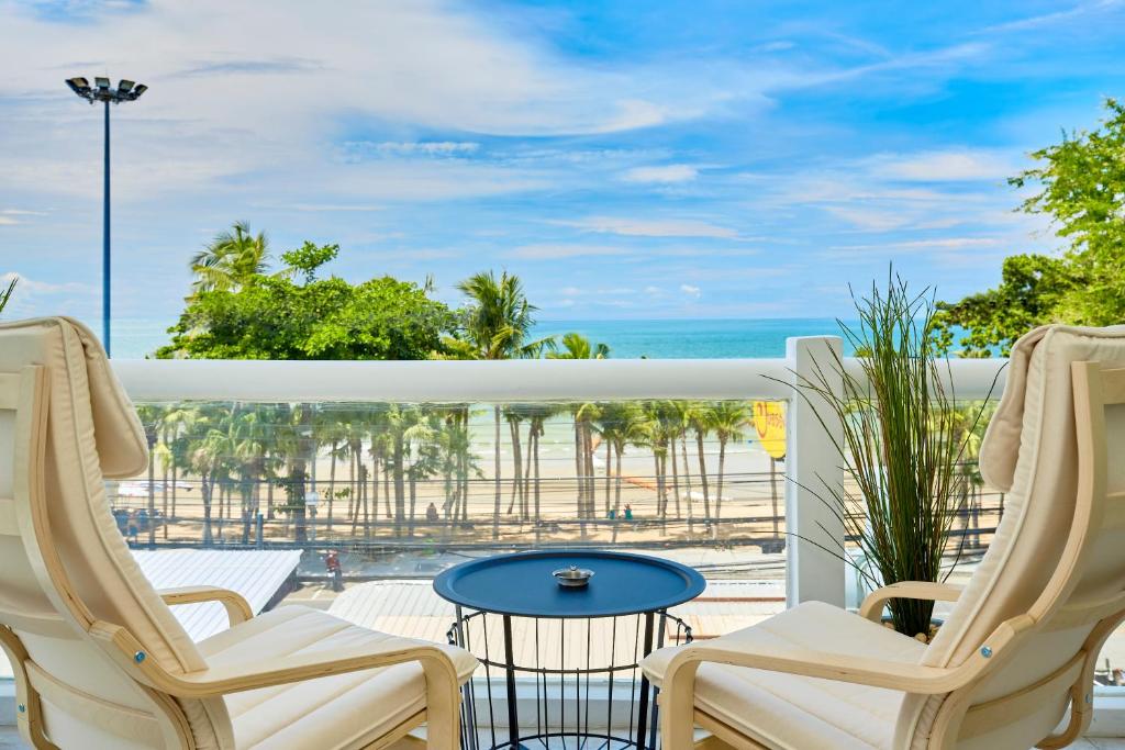 a balcony with chairs and a table and the ocean at LUXURIOUS APARTMENT on JOMTIEN BEACH ROAD in Jomtien Beach