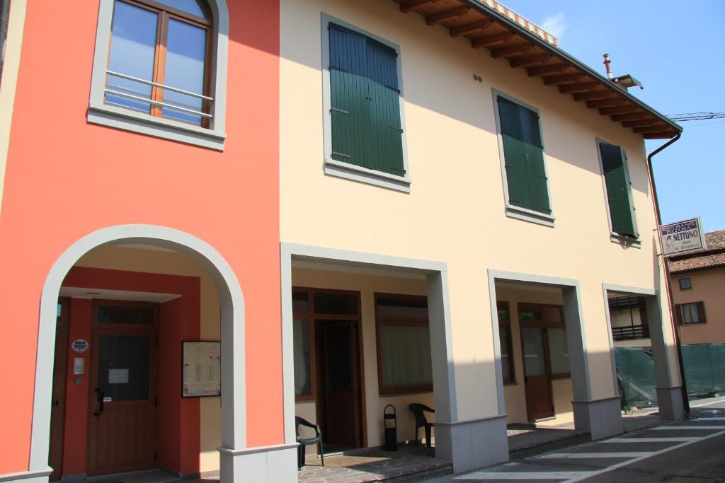 an orange and white building with green shutters at Bed & Breakfast Nettuno in Comun Nuovo