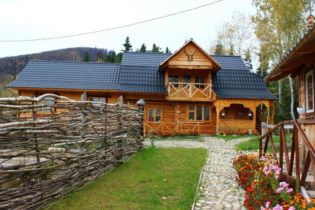 una casa de madera con una valla delante en Skhovanka Dovbusha en Migovo