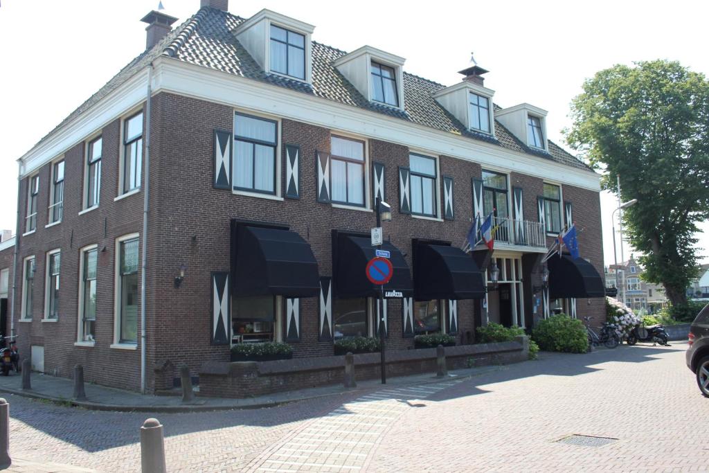 duży budynek z czerwonej cegły z czarnymi markizami w obiekcie Het Rechthuis w mieście Uithoorn