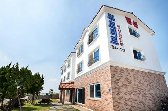 a building with a sign on the side of it at Purmir Pension in Seogwipo