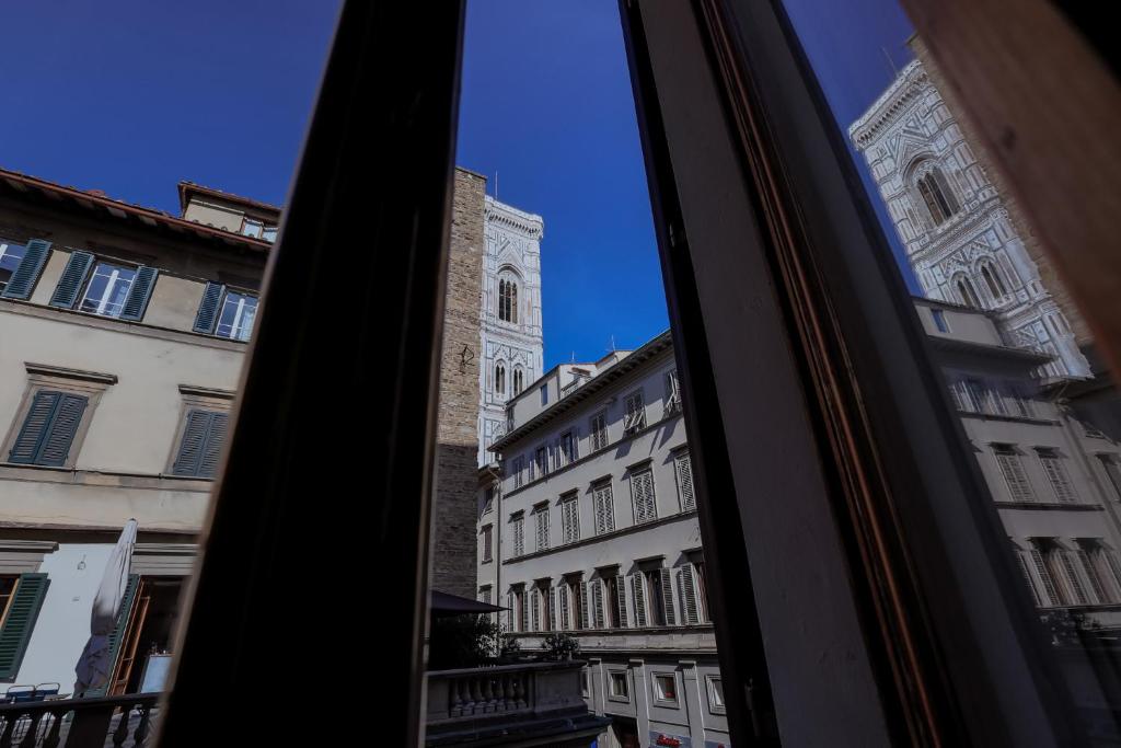 una ventana con vistas a un edificio con una torre de reloj en Firenze Rentals Suite Art, en Florencia